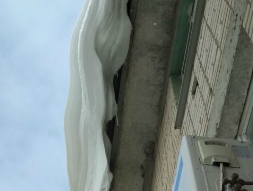 Огромные снежные сугробы свисают с крыши детской поликлиники в Новочеркасске